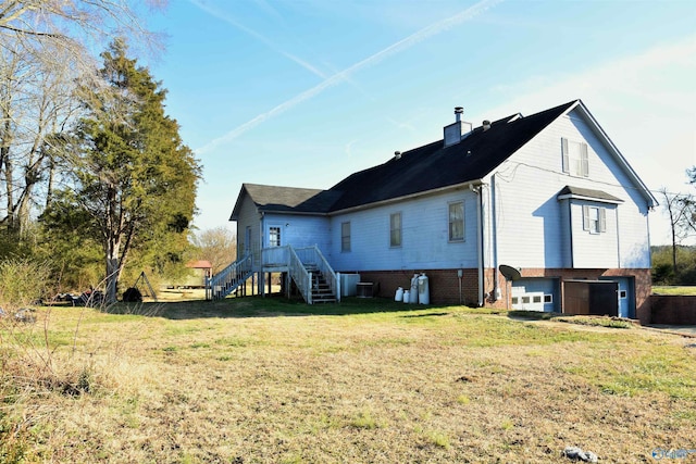 back of property featuring a garage, central air condition unit, and a lawn