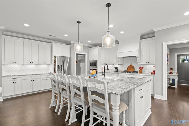 kitchen with decorative light fixtures, a center island with sink, stainless steel appliances, and dark wood-type flooring