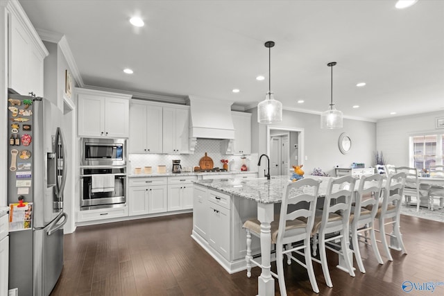 kitchen featuring dark hardwood / wood-style floors, white cabinets, custom range hood, stainless steel appliances, and decorative light fixtures