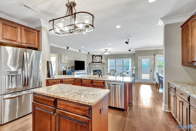 kitchen featuring visible vents, open floor plan, a center island, stainless steel appliances, and crown molding