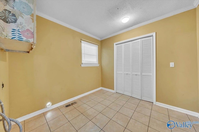 unfurnished bedroom featuring a textured ceiling, a closet, crown molding, light tile patterned floors, and baseboards