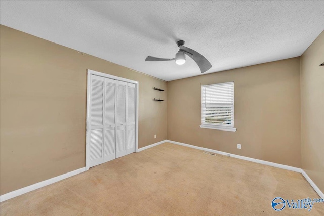 unfurnished bedroom featuring baseboards, carpet flooring, a closet, a textured ceiling, and a ceiling fan