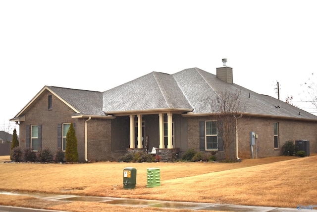 view of front of house with cooling unit, covered porch, and a front lawn