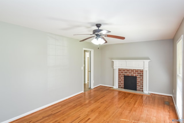 unfurnished living room featuring hardwood / wood-style floors, ceiling fan, and a brick fireplace