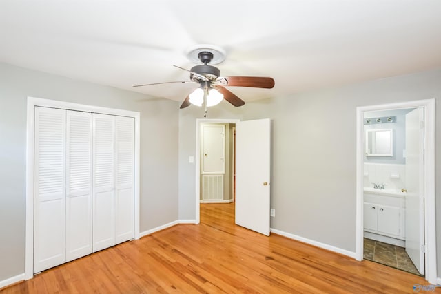 unfurnished bedroom featuring ceiling fan, sink, light hardwood / wood-style flooring, a closet, and ensuite bathroom