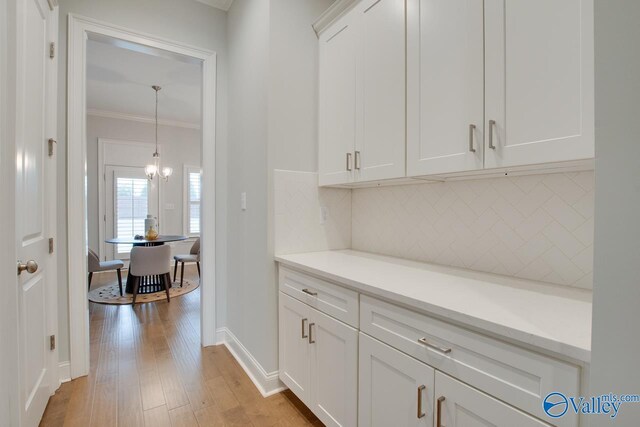 corridor with a notable chandelier, light hardwood / wood-style floors, and crown molding