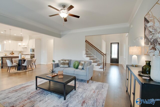 living room featuring light hardwood / wood-style floors, ceiling fan, and crown molding