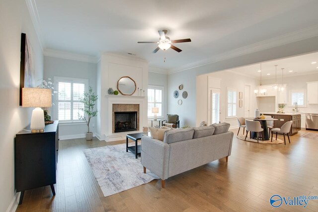 living room featuring hardwood / wood-style flooring, ceiling fan with notable chandelier, ornamental molding, and sink