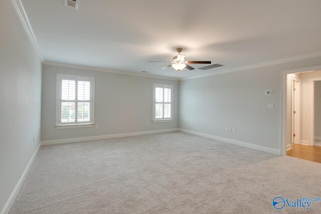 empty room with a healthy amount of sunlight, crown molding, and light colored carpet