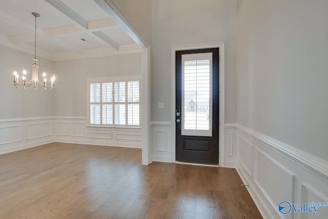 foyer entrance with coffered ceiling, ornamental molding, a notable chandelier, beam ceiling, and wood-type flooring