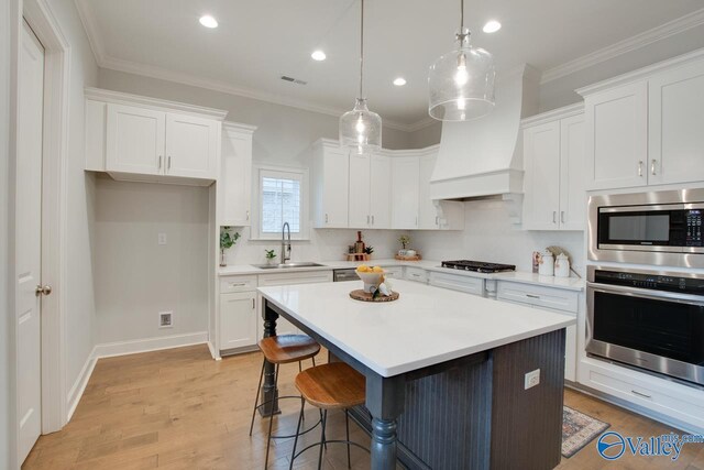 kitchen featuring white cabinets, sink, hanging light fixtures, a kitchen island, and stainless steel appliances