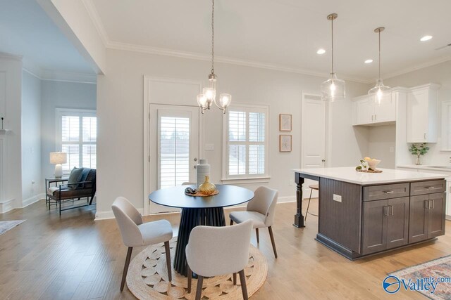 kitchen featuring white cabinets, light hardwood / wood-style flooring, ornamental molding, a wealth of natural light, and decorative light fixtures