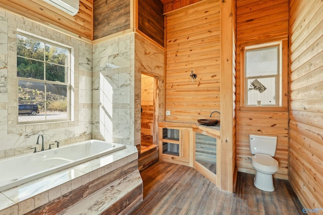 bathroom with hardwood / wood-style floors, a washtub, wood walls, and toilet