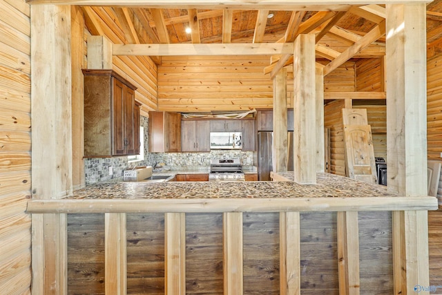 kitchen with tasteful backsplash, kitchen peninsula, stone counters, and appliances with stainless steel finishes