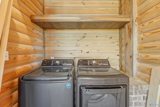 laundry room featuring wood walls and washing machine and dryer