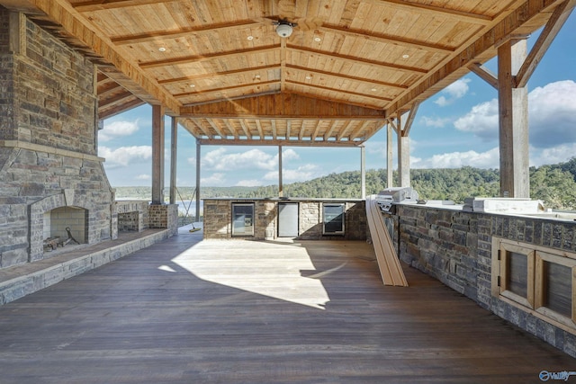 wooden deck with an outdoor stone fireplace, area for grilling, and exterior kitchen