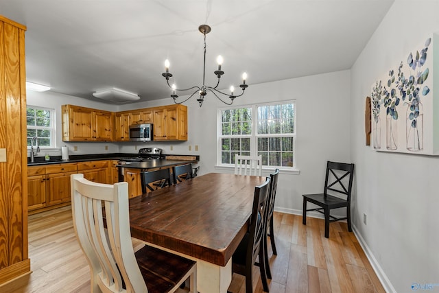 dining space featuring a notable chandelier, sink, and light wood-type flooring