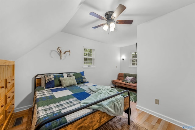 bedroom with ceiling fan, vaulted ceiling, and wood-type flooring