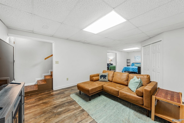 living room featuring a paneled ceiling and dark hardwood / wood-style flooring