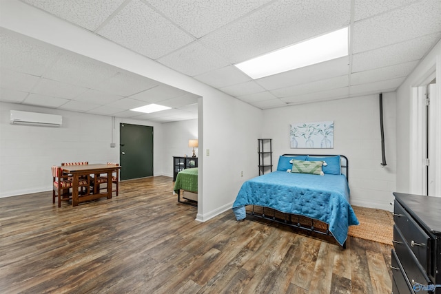 bedroom featuring dark hardwood / wood-style flooring, a paneled ceiling, and a wall mounted AC