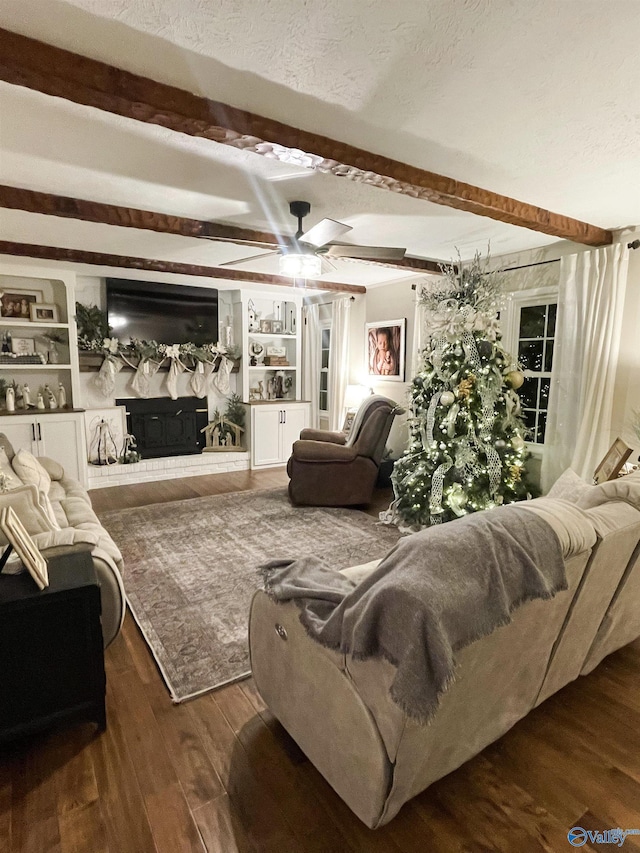 living room featuring dark hardwood / wood-style flooring, ceiling fan, a textured ceiling, and beamed ceiling