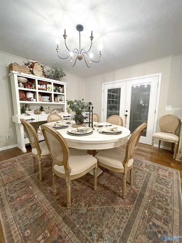 dining area featuring french doors, a textured ceiling, an inviting chandelier, and dark wood-type flooring