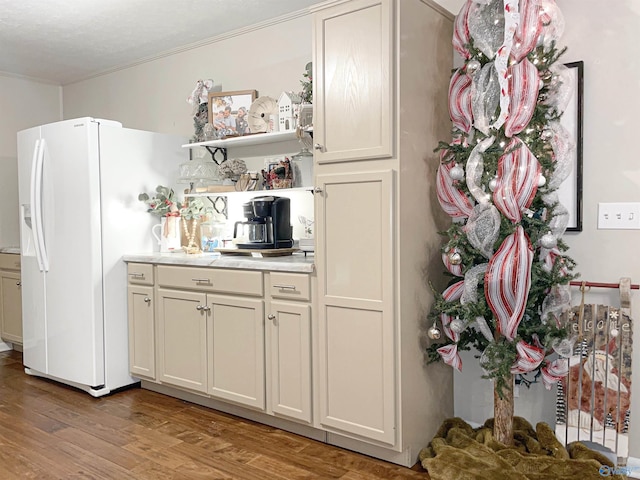 kitchen with white fridge with ice dispenser, ornamental molding, and light wood-type flooring