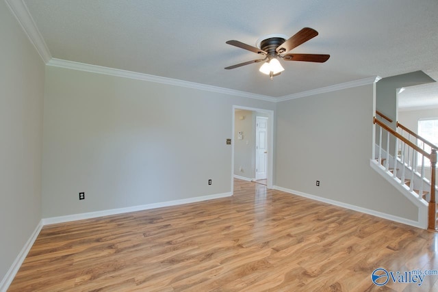 unfurnished room with ceiling fan, light wood finished floors, ornamental molding, baseboards, and stairway