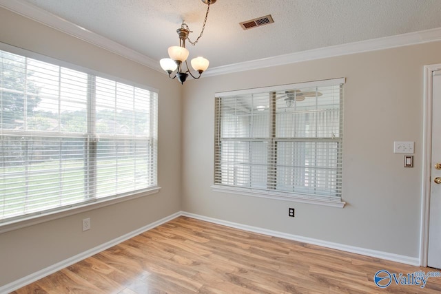 unfurnished room featuring a chandelier, ornamental molding, light wood-style flooring, baseboards, and a textured ceiling