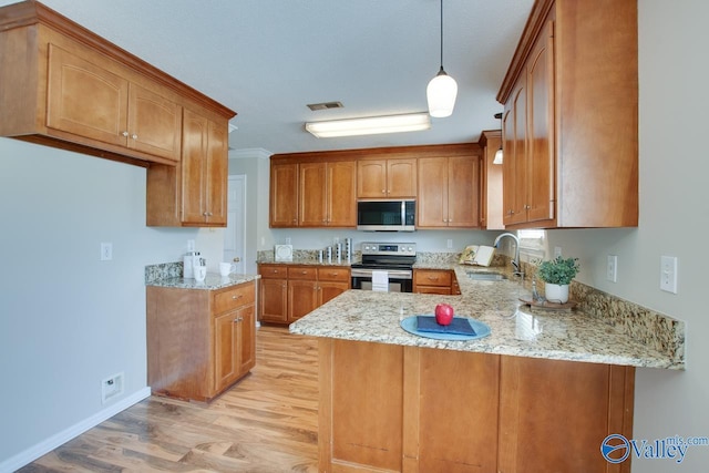 kitchen featuring stainless steel appliances, a sink, light wood-style floors, a peninsula, and light stone counters