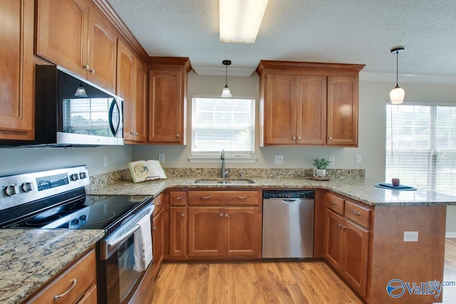 kitchen featuring stainless steel appliances, a sink, a peninsula, brown cabinets, and ornamental molding
