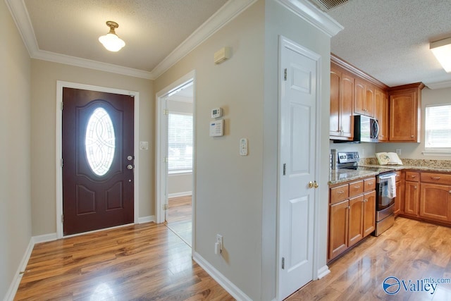 entrance foyer with light wood-style flooring, ornamental molding, a textured ceiling, and baseboards