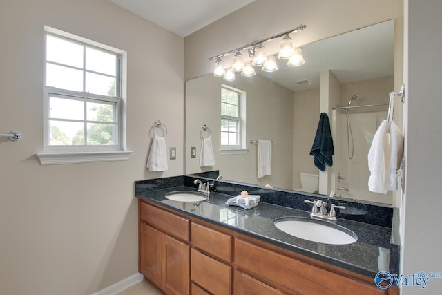 bathroom with toilet, a shower, and double vanity
