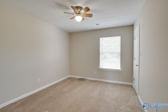 unfurnished room with light carpet, a ceiling fan, a textured ceiling, and baseboards