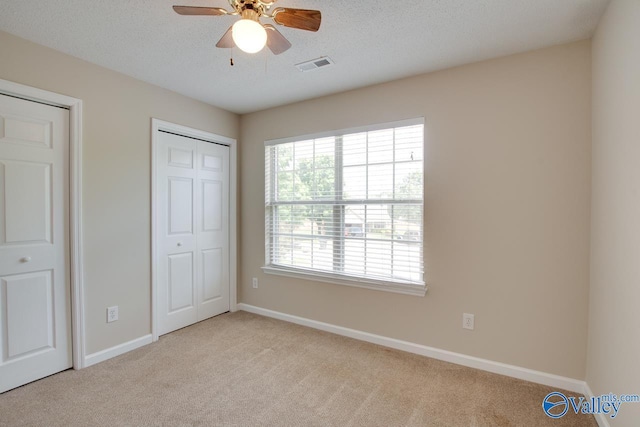 unfurnished bedroom featuring carpet flooring, baseboards, a textured ceiling, and a ceiling fan