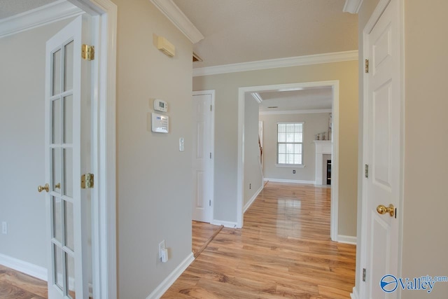 corridor featuring crown molding, light wood finished floors, and baseboards