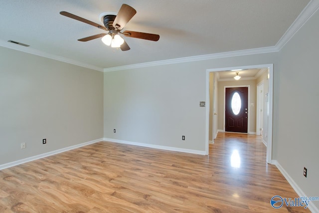 empty room with ornamental molding, a ceiling fan, light wood finished floors, and baseboards