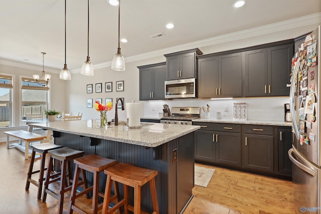 kitchen featuring a breakfast bar area, light stone countertops, visible vents, and appliances with stainless steel finishes
