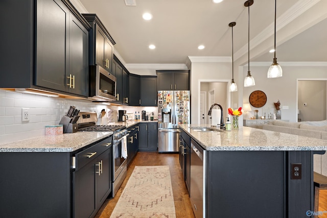 kitchen with a kitchen island with sink, crown molding, appliances with stainless steel finishes, and a sink
