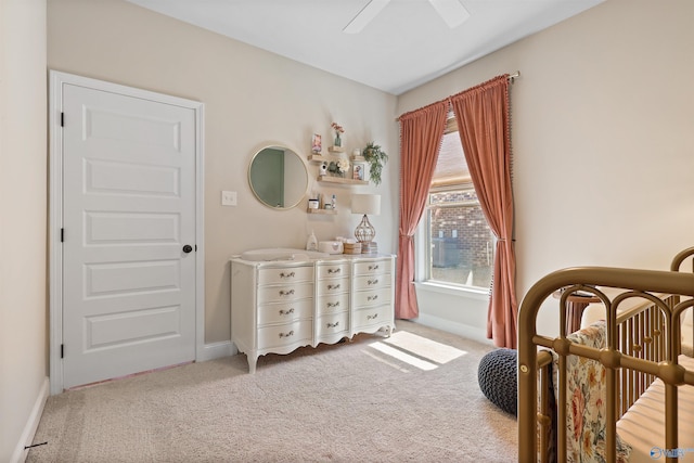 bedroom with ceiling fan, carpet, baseboards, and a crib