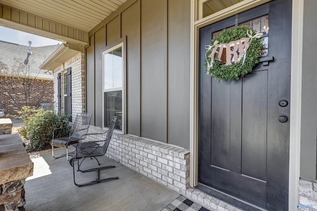 property entrance with covered porch, brick siding, and board and batten siding