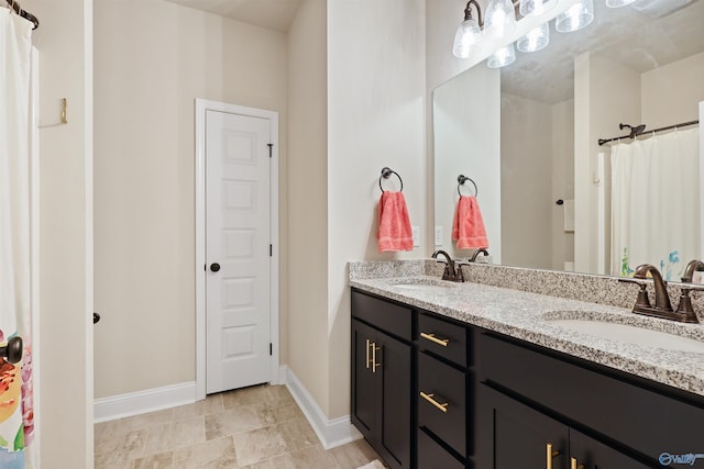 bathroom with a sink, double vanity, baseboards, and visible vents