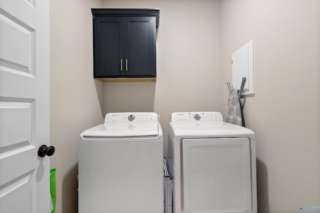 clothes washing area featuring separate washer and dryer and cabinet space