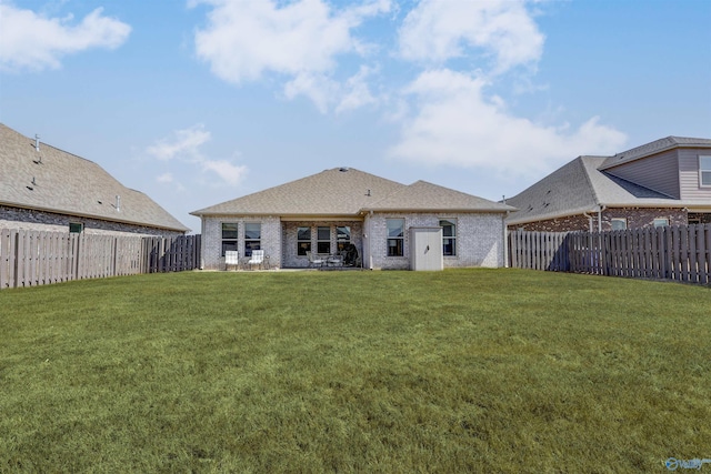 rear view of property featuring a fenced backyard, brick siding, and a lawn