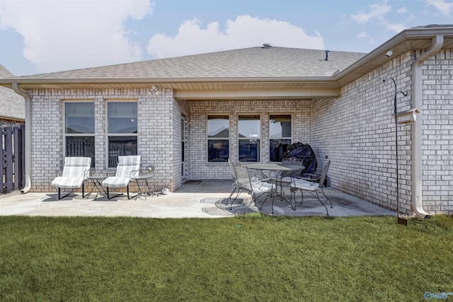 rear view of property featuring a yard, a patio area, roof with shingles, and brick siding