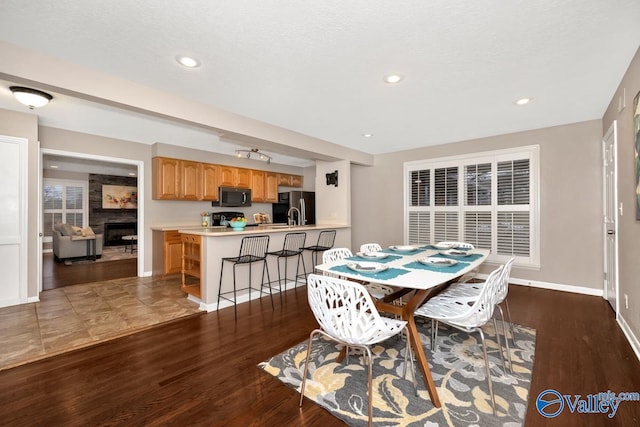 dining space with a fireplace, baseboards, wood finished floors, and recessed lighting