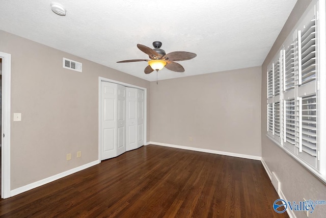 unfurnished bedroom with baseboards, a textured ceiling, visible vents, and wood finished floors