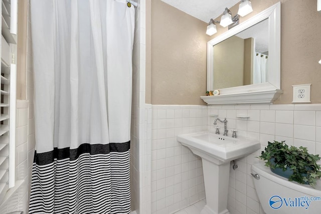 full bathroom featuring a wainscoted wall, toilet, tile walls, and a shower with curtain