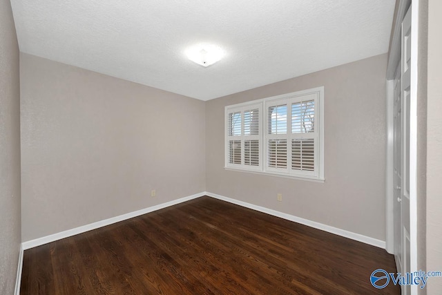 unfurnished bedroom featuring a textured ceiling, baseboards, and dark wood-style flooring