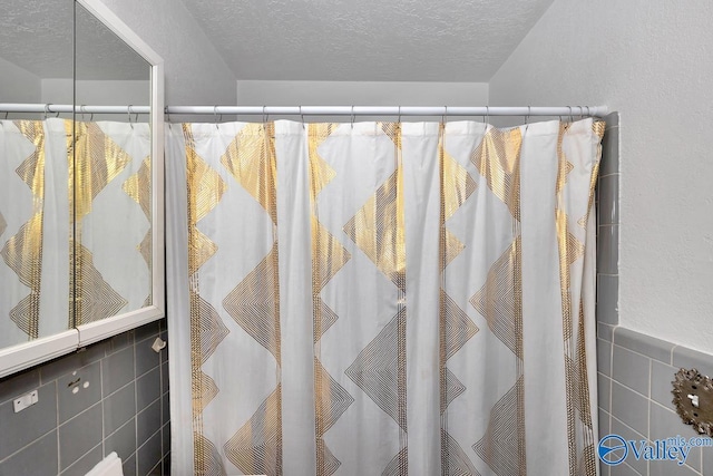 full bath featuring a textured ceiling, a shower with shower curtain, and tile walls